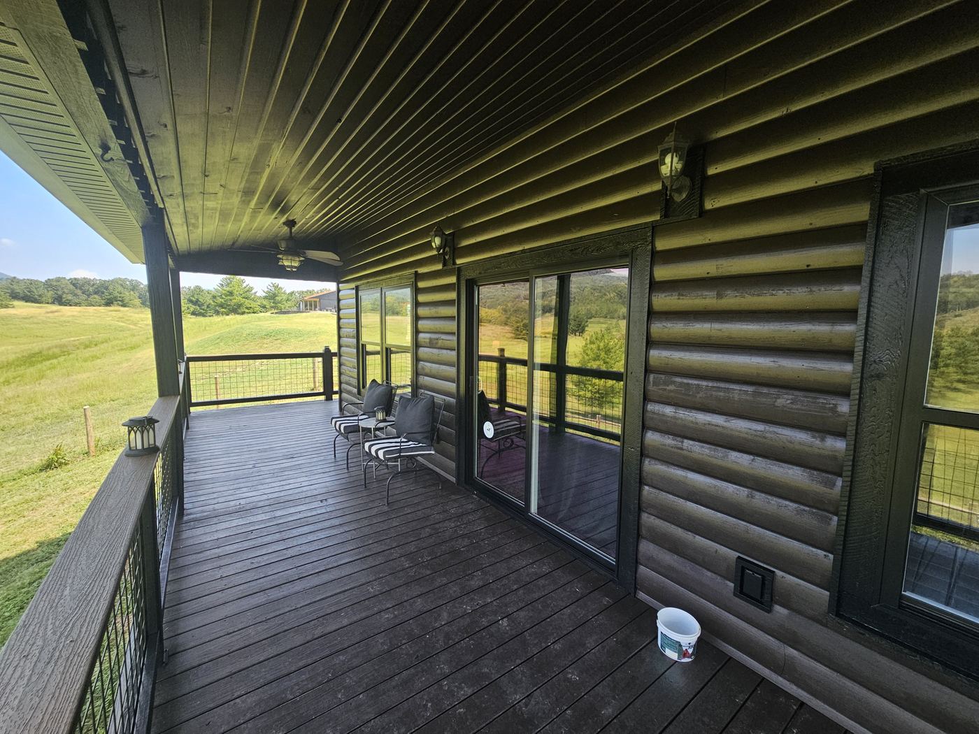 Stained log porch with sliding doors looking across pasture.