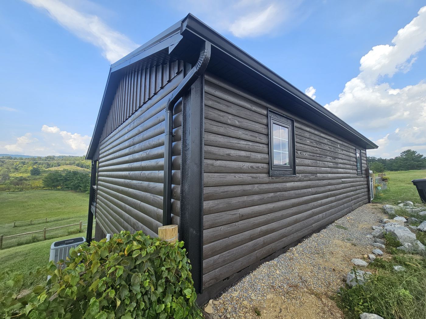 Dark-stained log cabin against a blue East Tennessee sky.