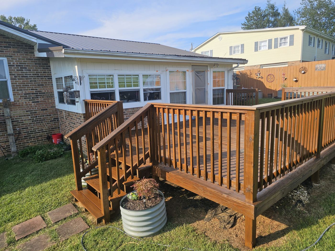 Freshly stained wood deck and railings on a brick home.