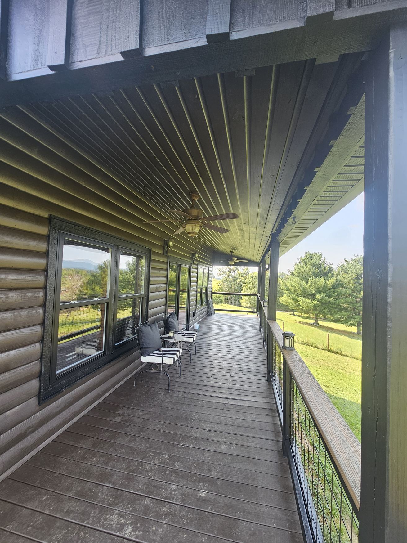 Freshly stained log cabin porch looking over green East Tennessee hills.