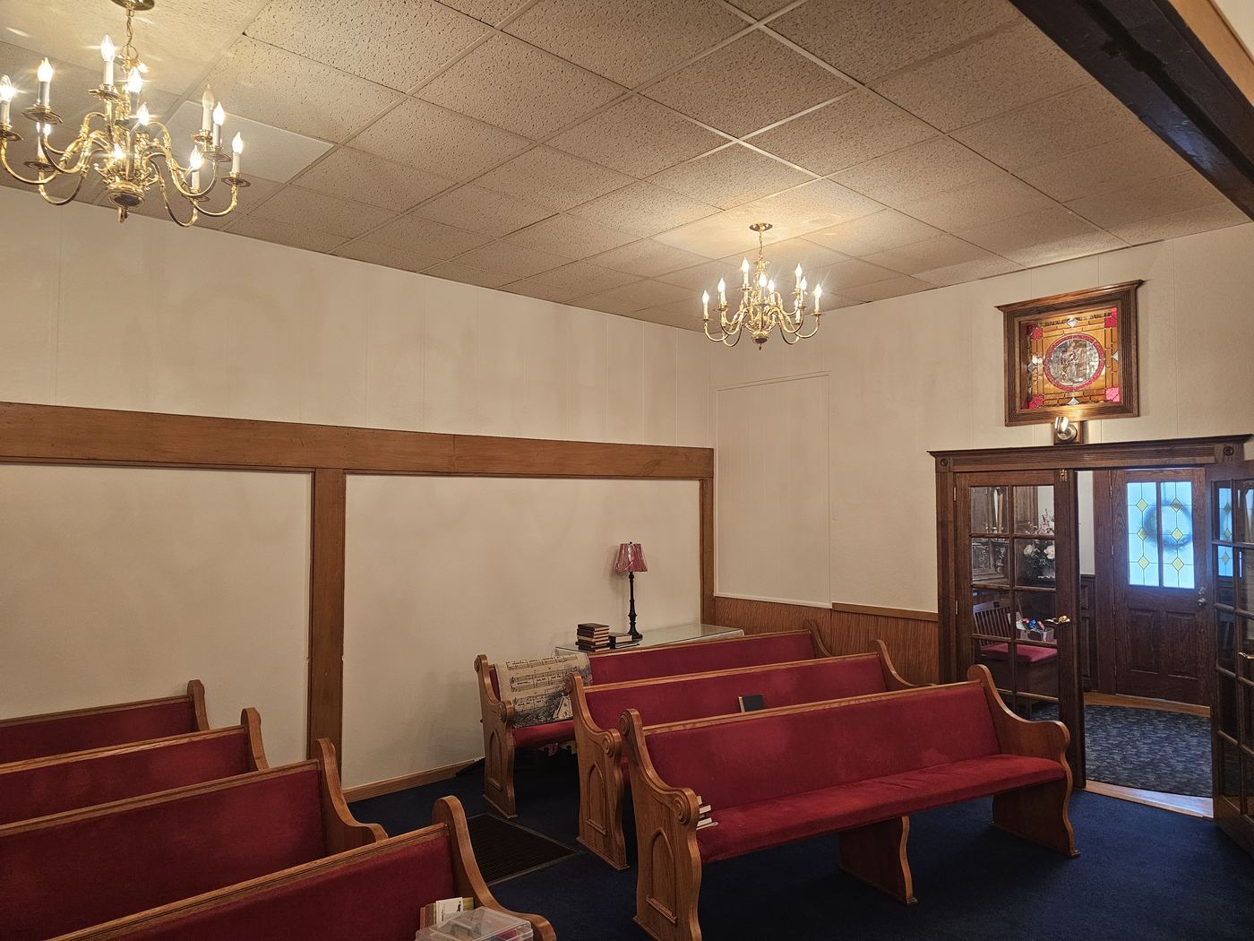 Church sanctuary with red pews, white walls, and stained glass.